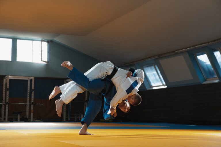 Two young judo fighters in kimono training martial arts in the gym with expression, in action and